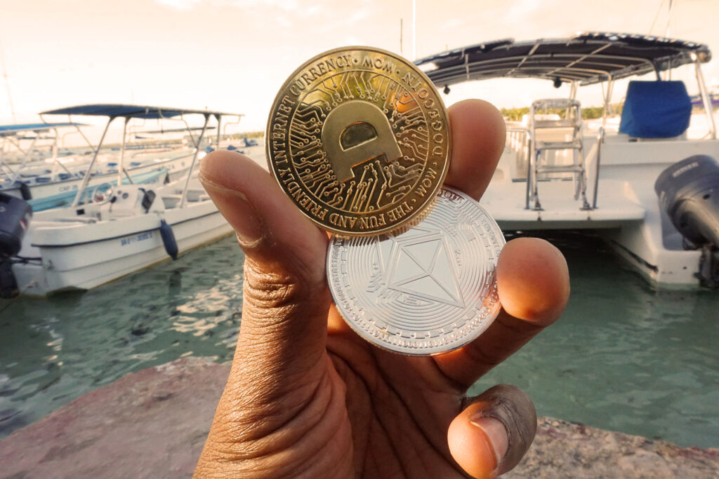 Dogecoin ($DOGE) and Ethereum ($ETH) Tokins Being Hand-held on a Caribbean bridge next to boats