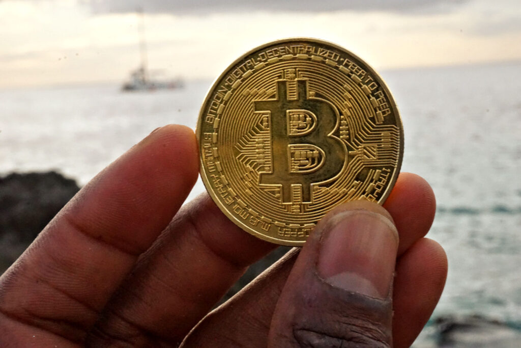 Bitcoin ($BTC) Token in Front of Sailboat Ⓒ 2023 – Crypto Coin Opps